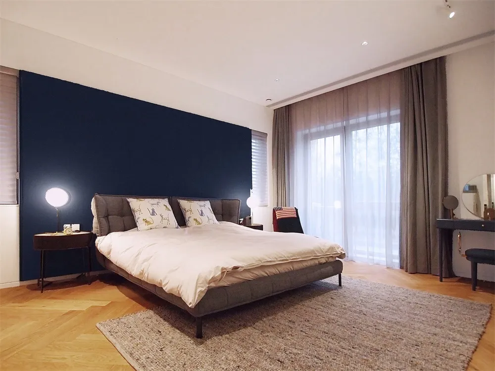 A modern minimalist bedroom featuring neutral-colored furniture and a dark headboard wall.
