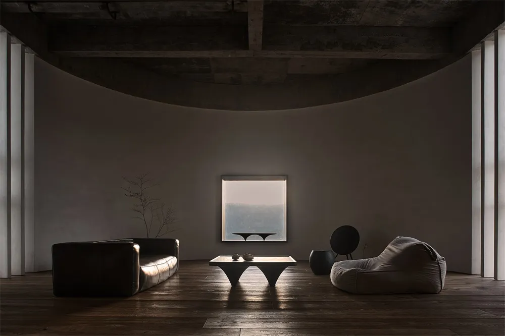 A minimalist living room with concrete furniture and a large window overlooking a serene landscape.