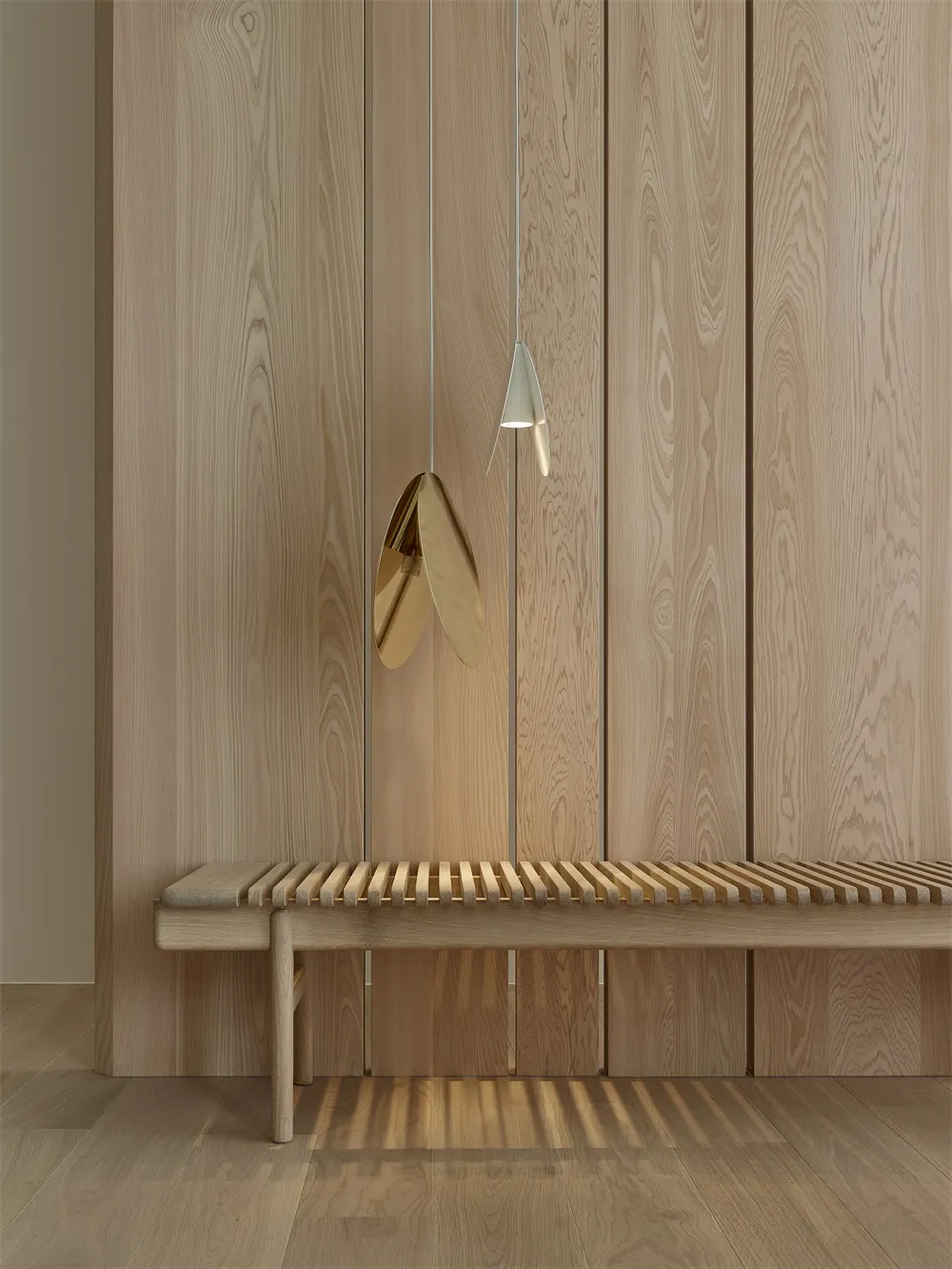 Minimalist wooden bench in a contemporary setting with a unique pendant light hanging above it.