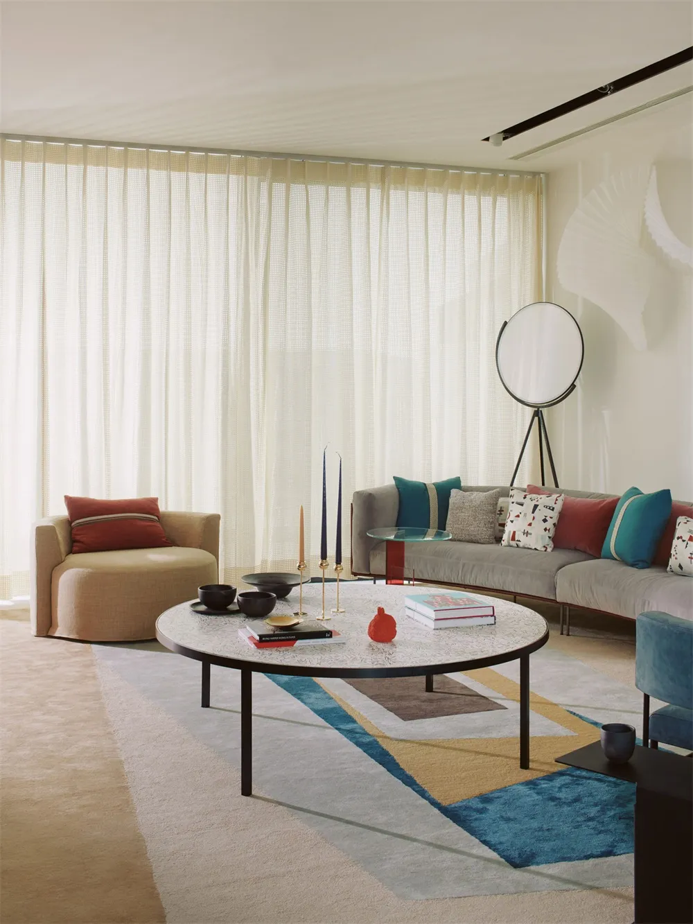 A modern living room with a circular coffee table, grey sofa, and fabric armchair.