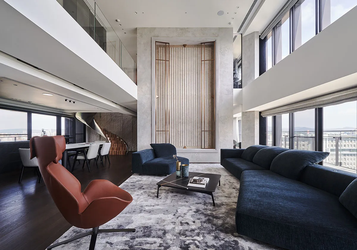 A modern living room featuring a large sectional sofa, armchair, and coffee table on a patterned rug.