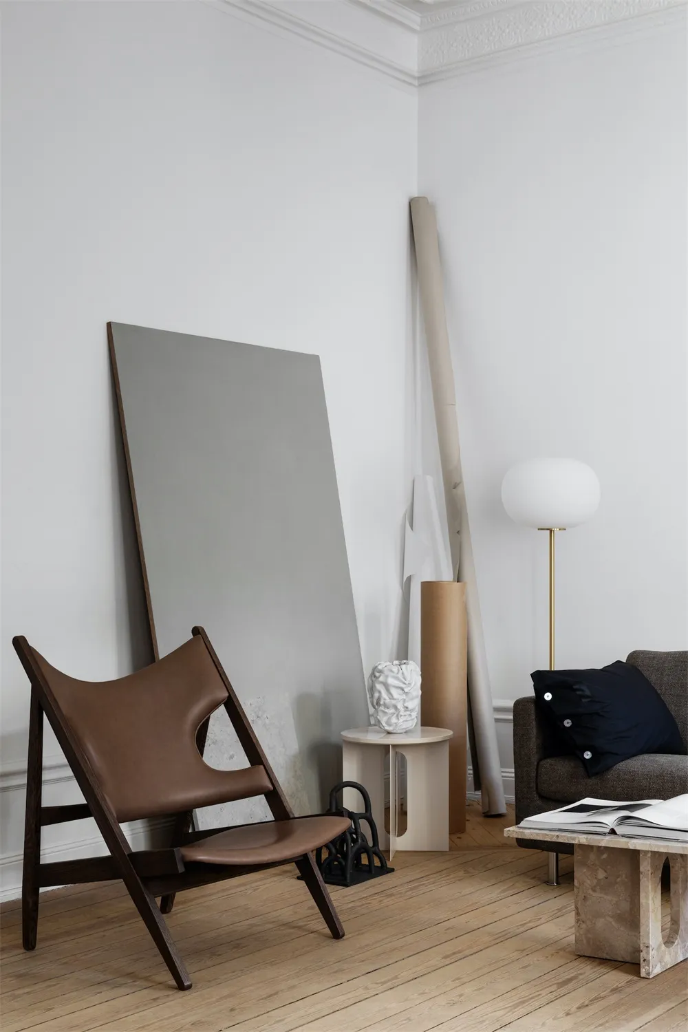 A modern minimalist living room featuring a sleek wooden chair, a contemporary sofa, simple decor, and a warm, inviting ambia