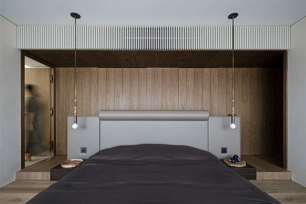 A minimalist bedroom with a wooden headboard and wall paneling.