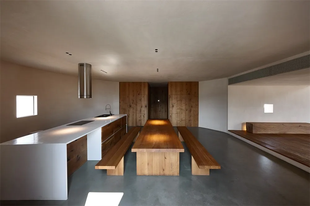 A minimalist kitchen with wooden elements and a concrete floor.