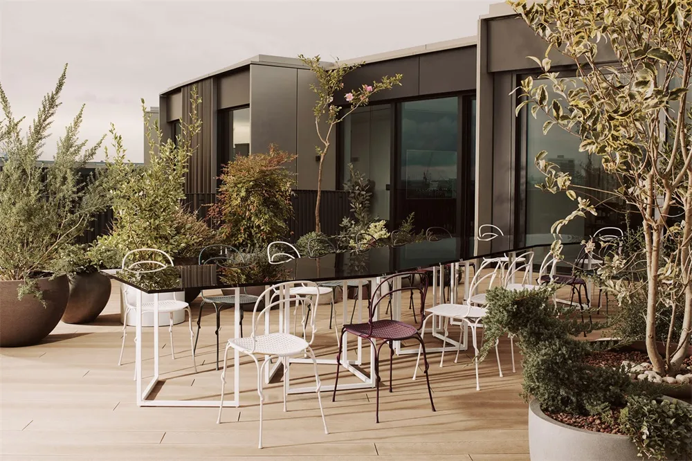 A modern rooftop patio featuring metal furniture and concrete ground.
