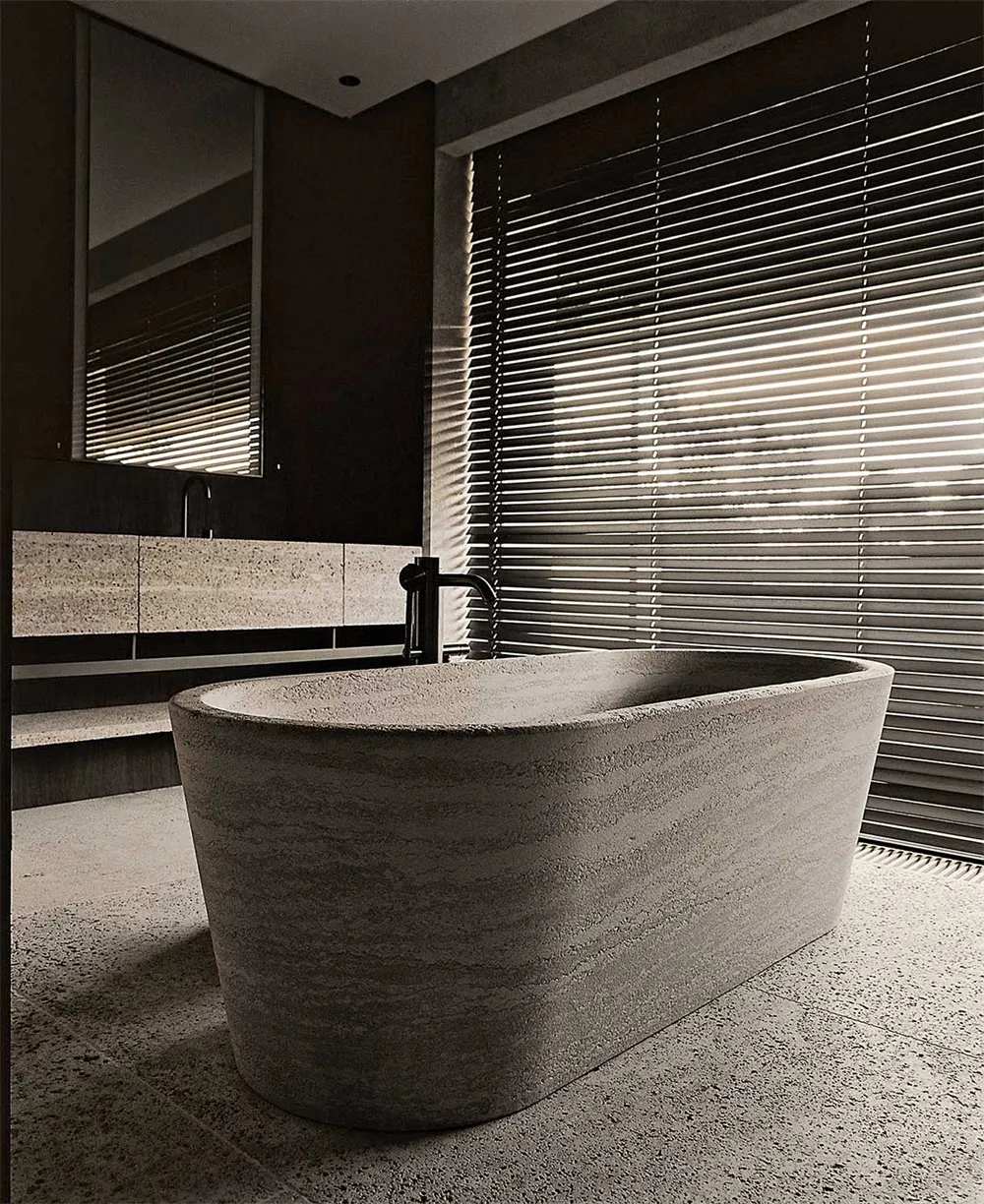 A modern bathroom with a freestanding bath made of concrete, featuring a concrete floor and walls, and a window with horizont