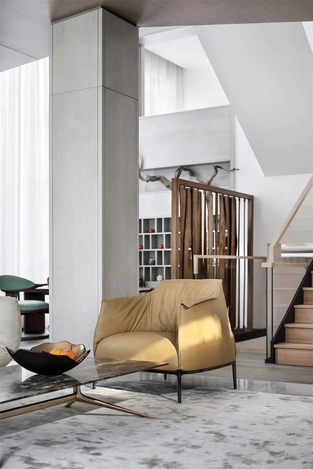 A modern living room with a beige leather armchair, a glass and metal coffee table, and a wooden floor.
