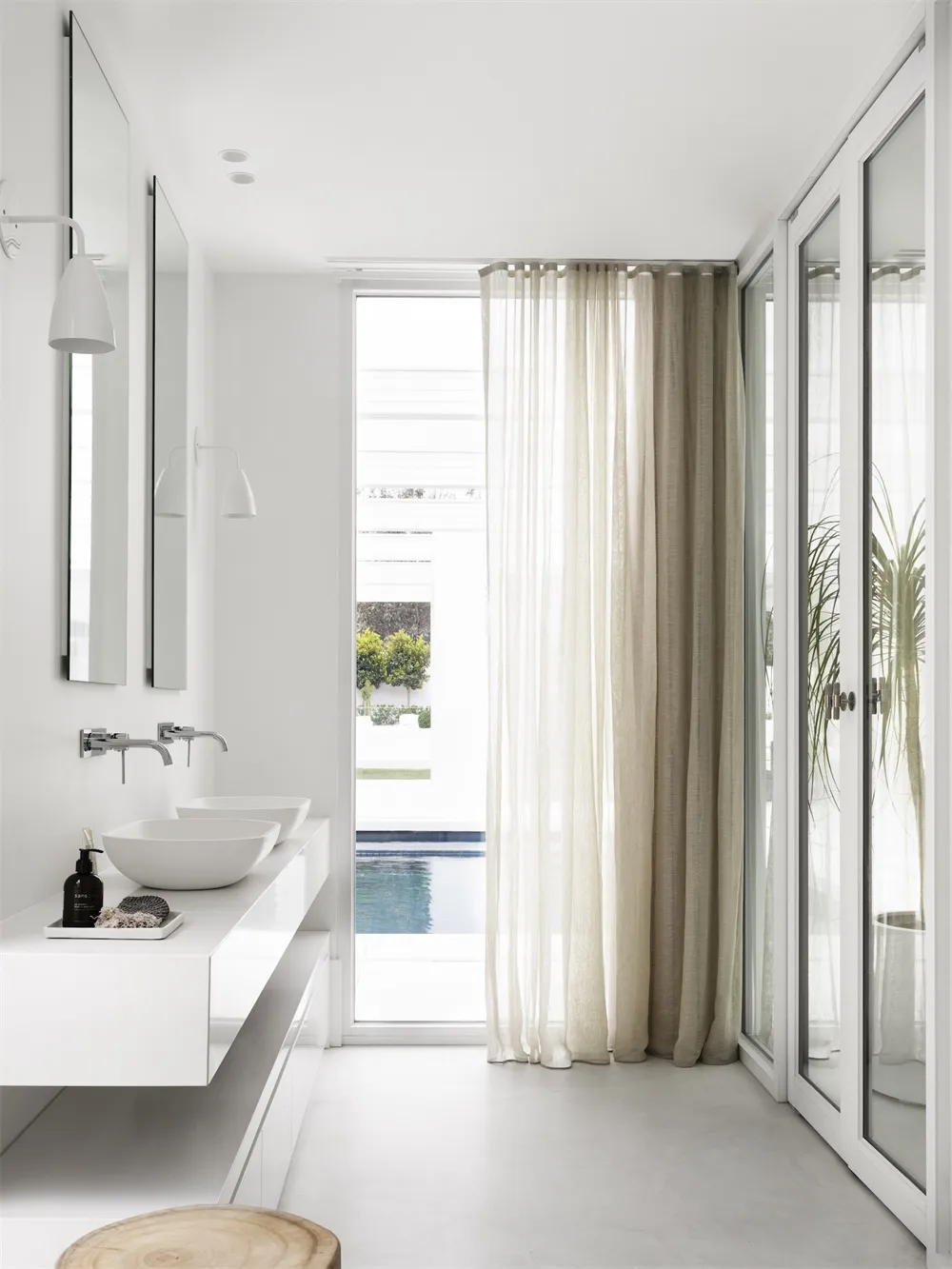 A modern bathroom with white walls, glass walls, marble elements, a floating vanity, and a curtain.