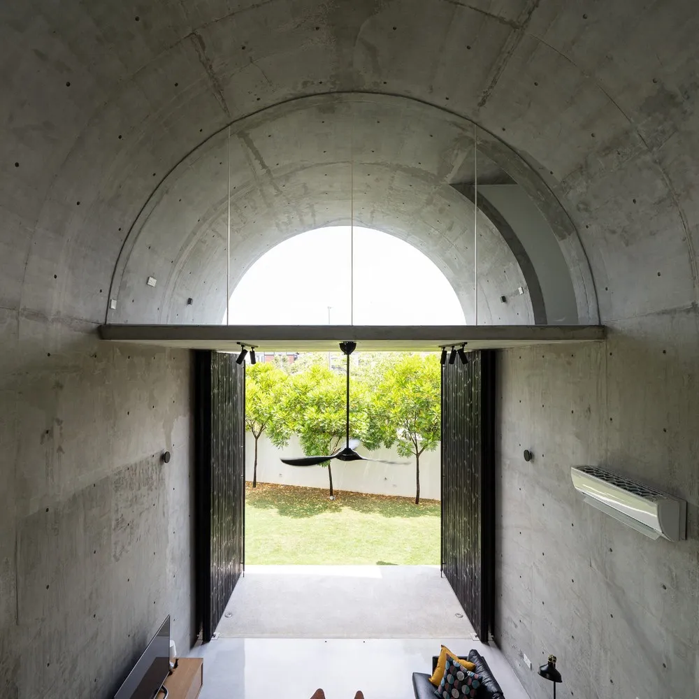 A modern interior design featuring a concrete arch with natural light and greenery outside.