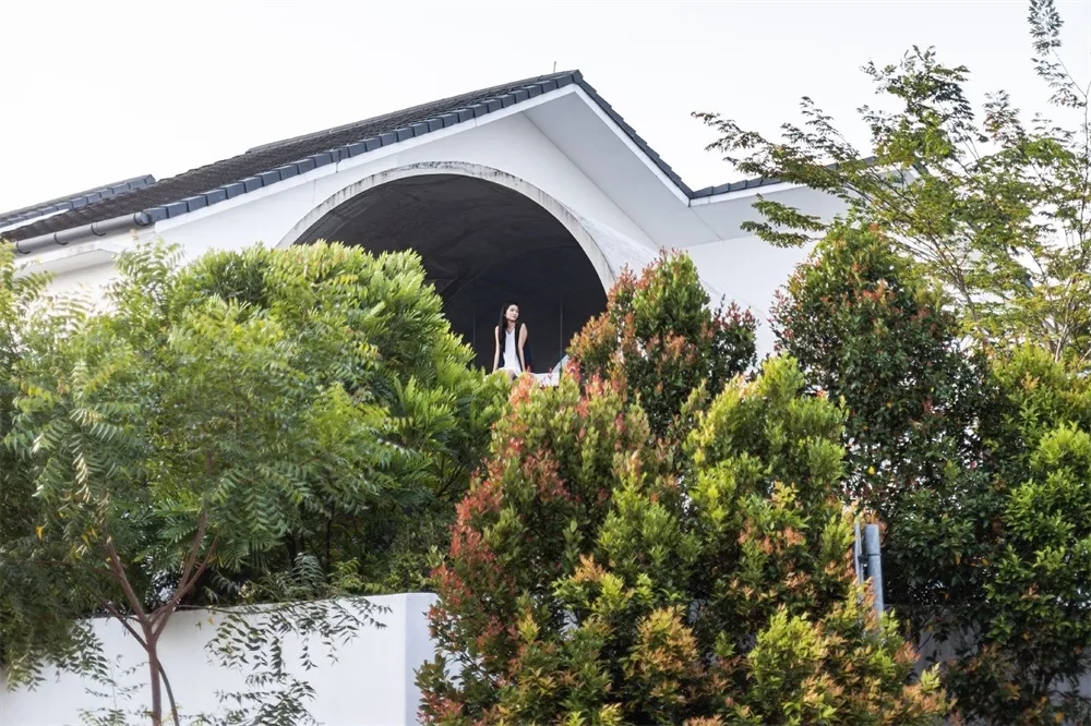 一座擁有混凝土牆面的現代外觀建築，四周環繞綠意植物。