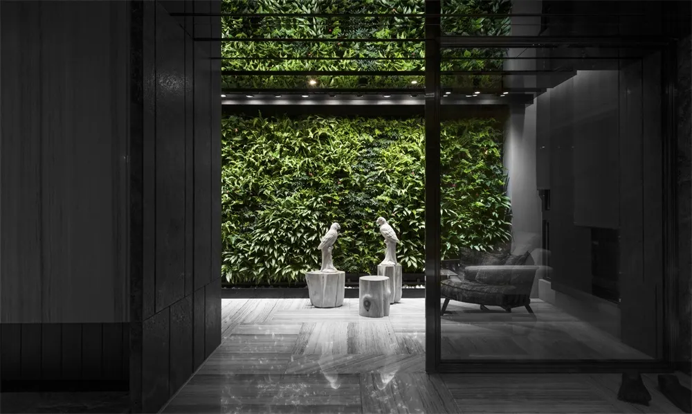 A minimalistic, industrial-style lobby with a concrete floor and a green living wall.