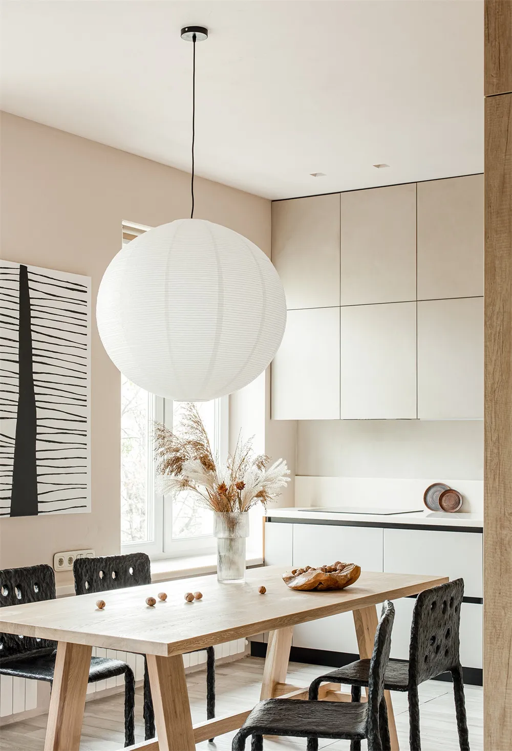Minimalist kitchen featuring wooden table, glass vase of dry flowers, and concrete cabinets