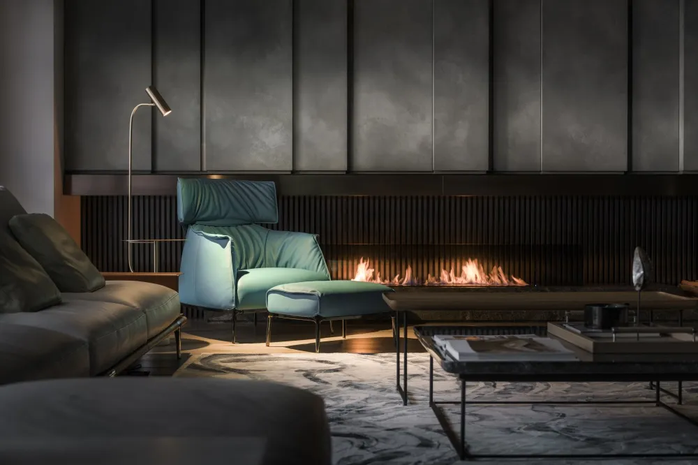 Modern living room with concrete, leather, and metal furniture, warm lighting, and a warm fireplace.