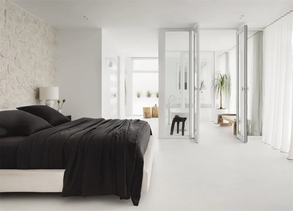Modern minimalist bedroom featuring a black and white color scheme, with a bed adorned with black bedding against a white wal