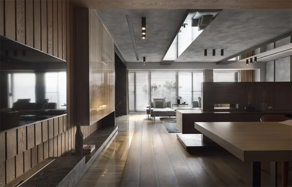 Modern minimalist living room with wooden flooring, glass walls, and a concrete ceiling.