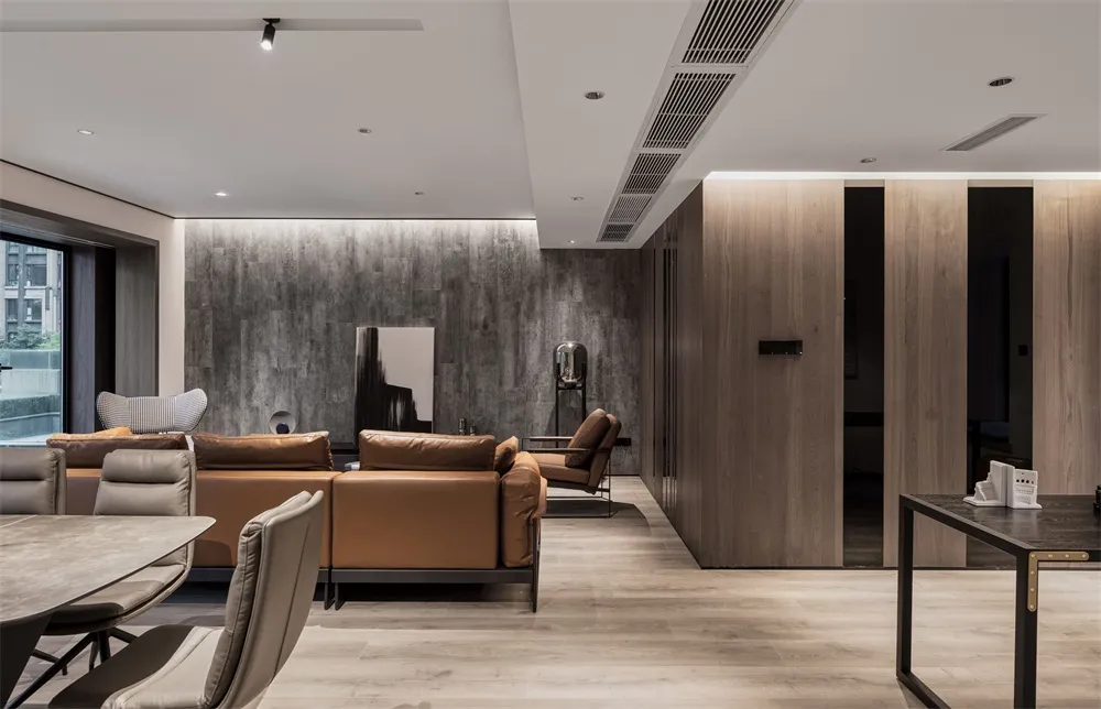 A modern living and dining room with concrete, wood, and leather materials.