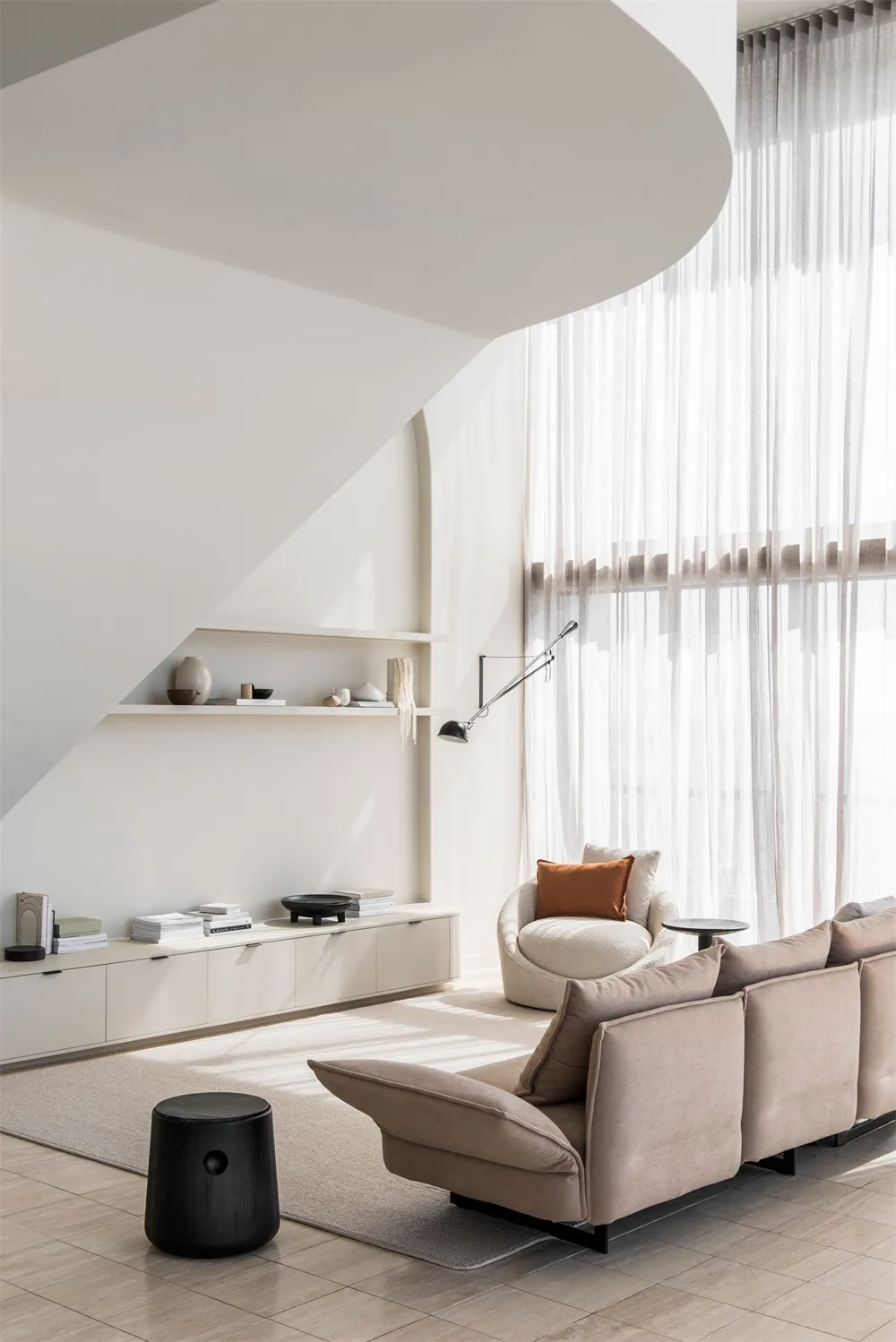 Modern minimalist living room with a fabric couch, white architectural features, and white shelves.