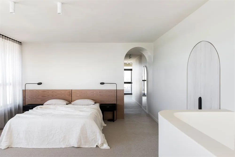 Modern minimalist bedroom featuring a wooden headboard and white bedding