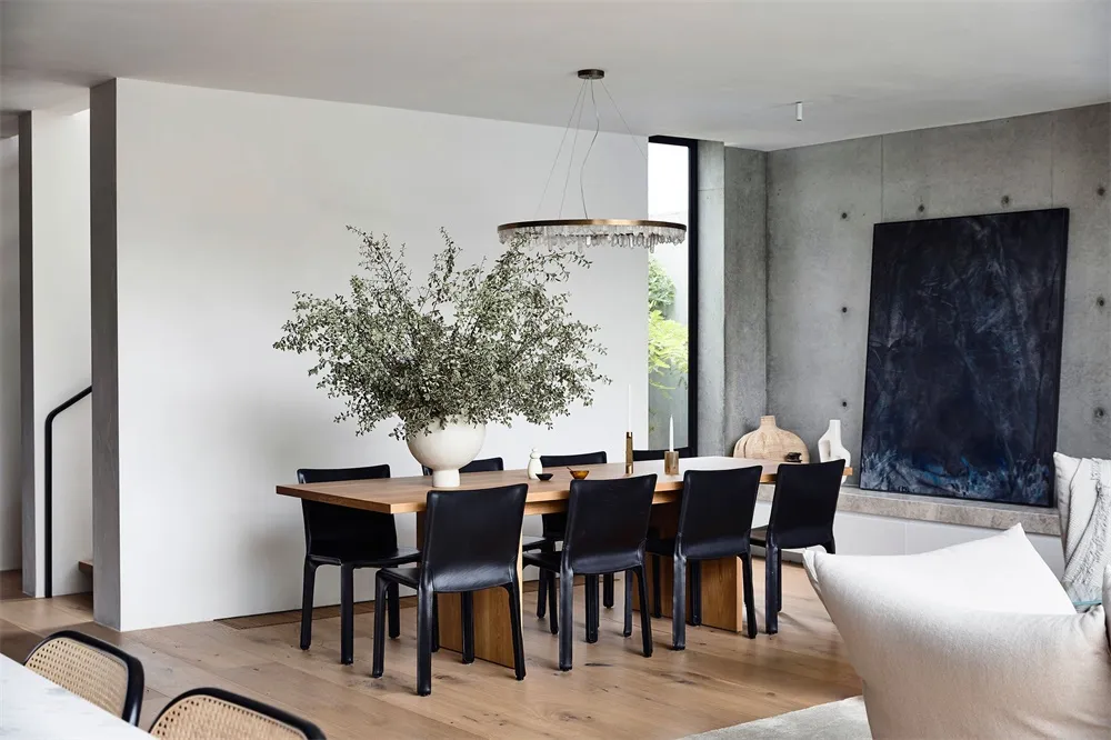 A modern dining room with a wooden table and black chairs.
