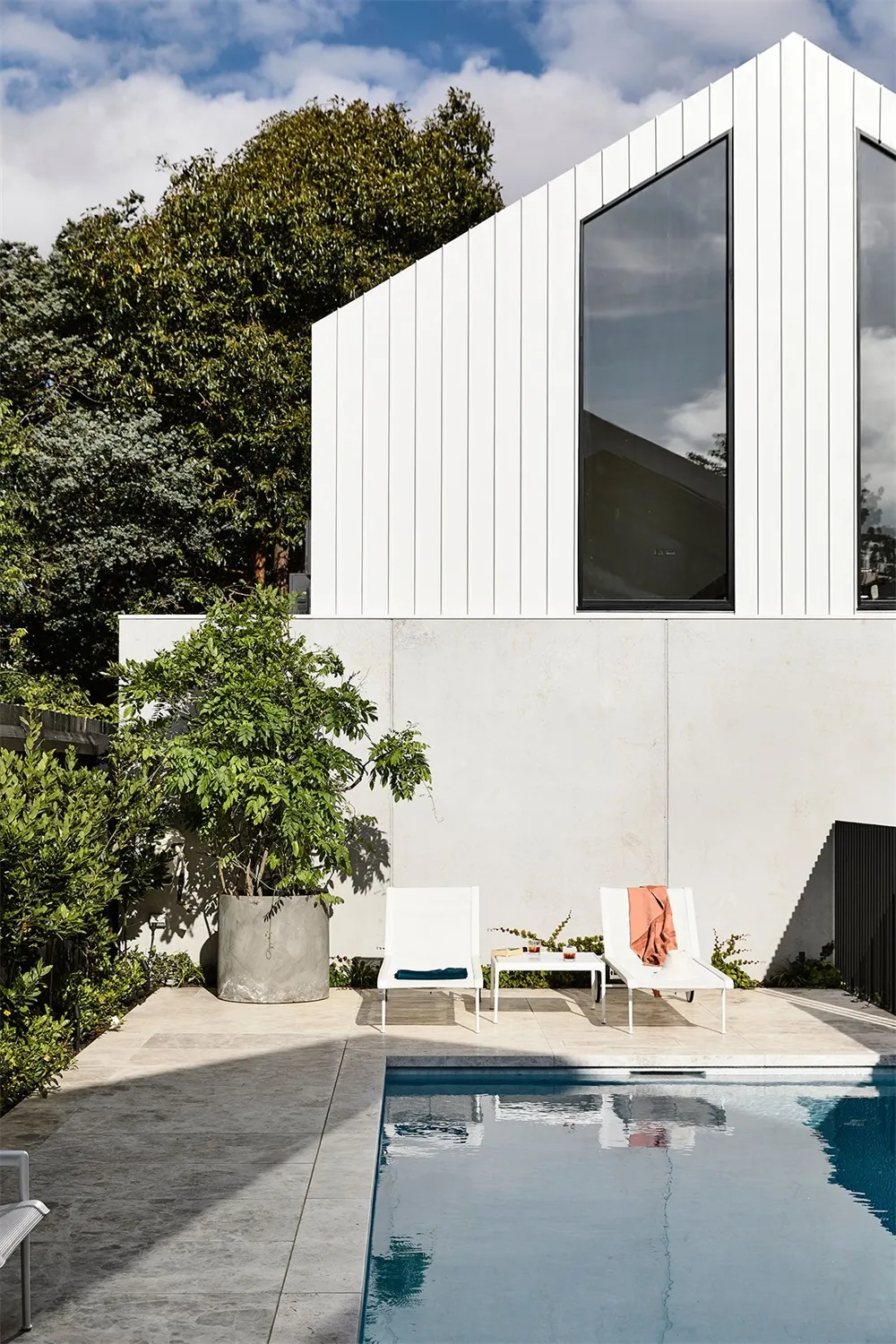 A modern home exterior features concrete and glass materials with a swimming pool.