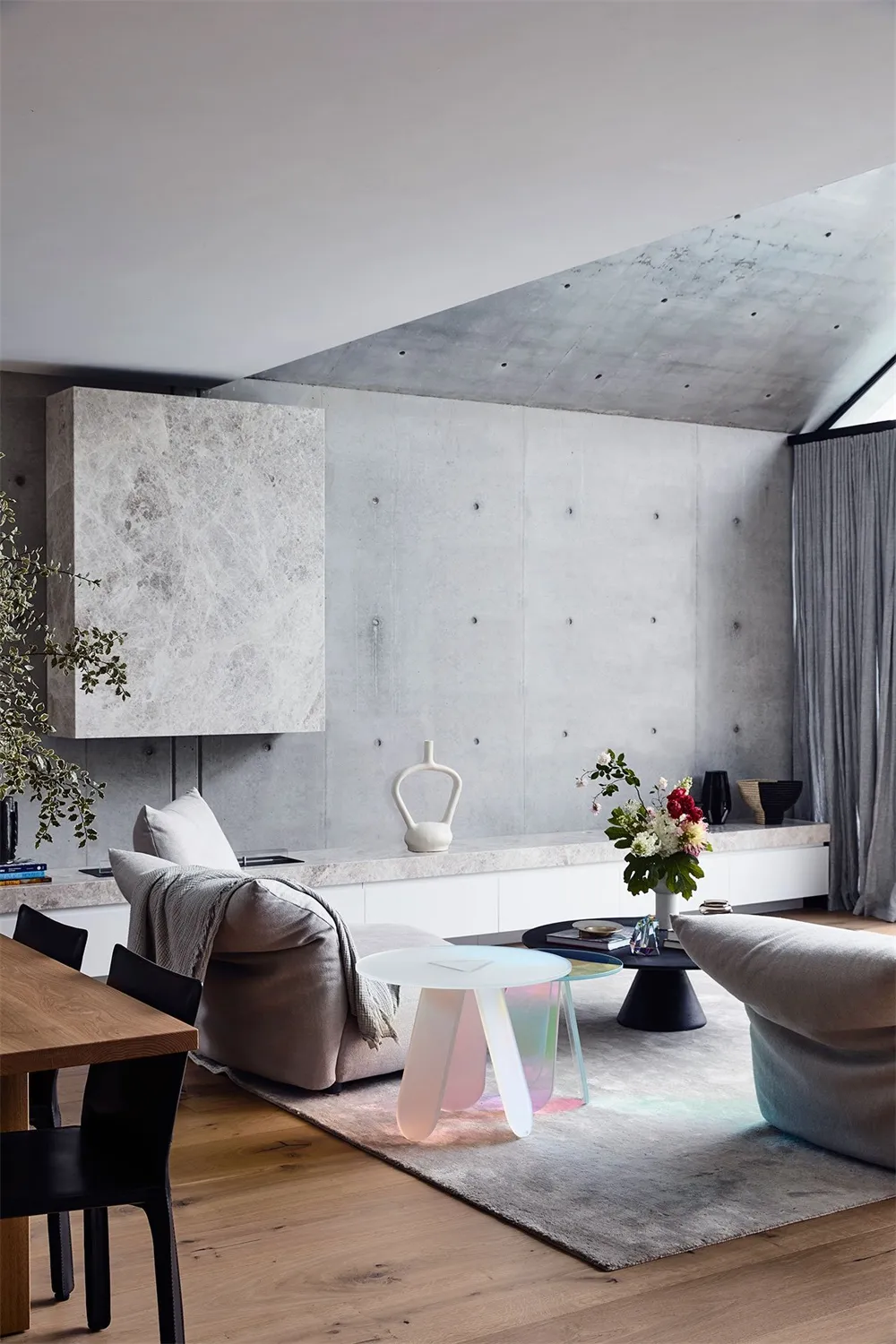 A modern living room with concrete walls, wooden flooring, and contemporary furniture and design elements.
