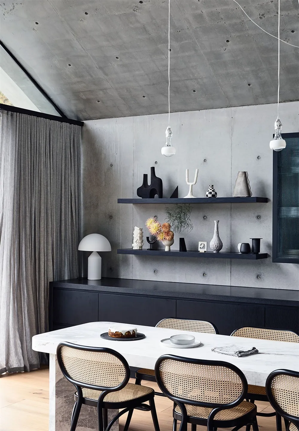 A minimalist dining room with concrete walls and white marble table.