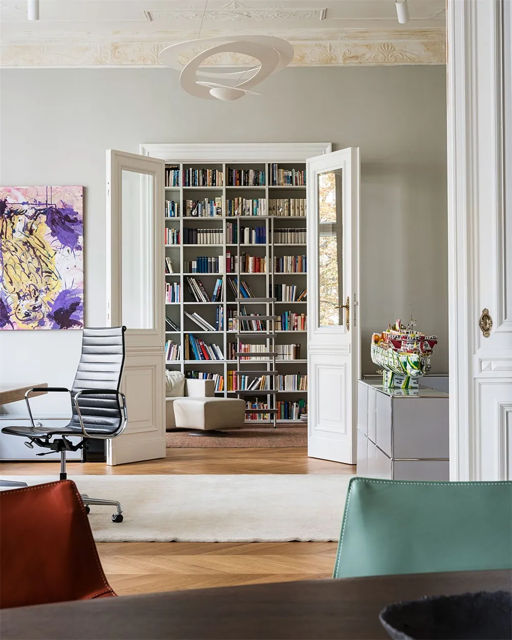 Modern home library with bookshelves, chairs, and a rug.
