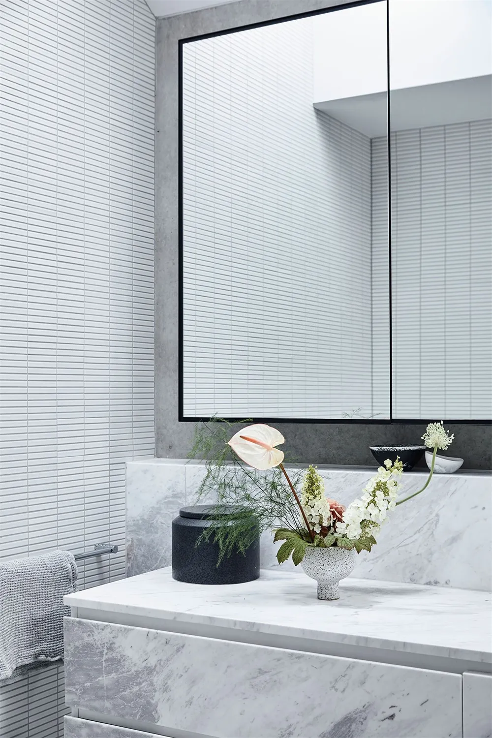 A modern minimalist bathroom with marble countertop, white tiles, and concrete wall.