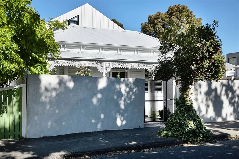 A modern, white house with a concrete wall on the street.