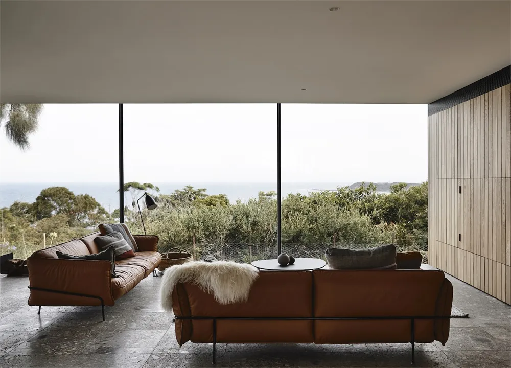 Comfortable seating area with a view of greenery, featuring leather sofas and wooden elements.