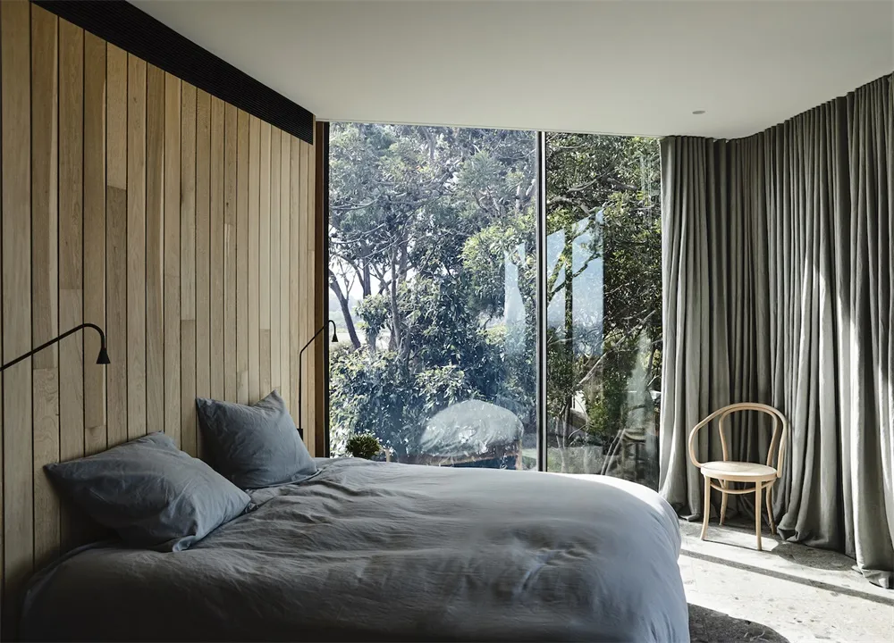 Minimalist bedroom featuring a bed with wood paneling, glass windows, and a gray fabric headboard.
