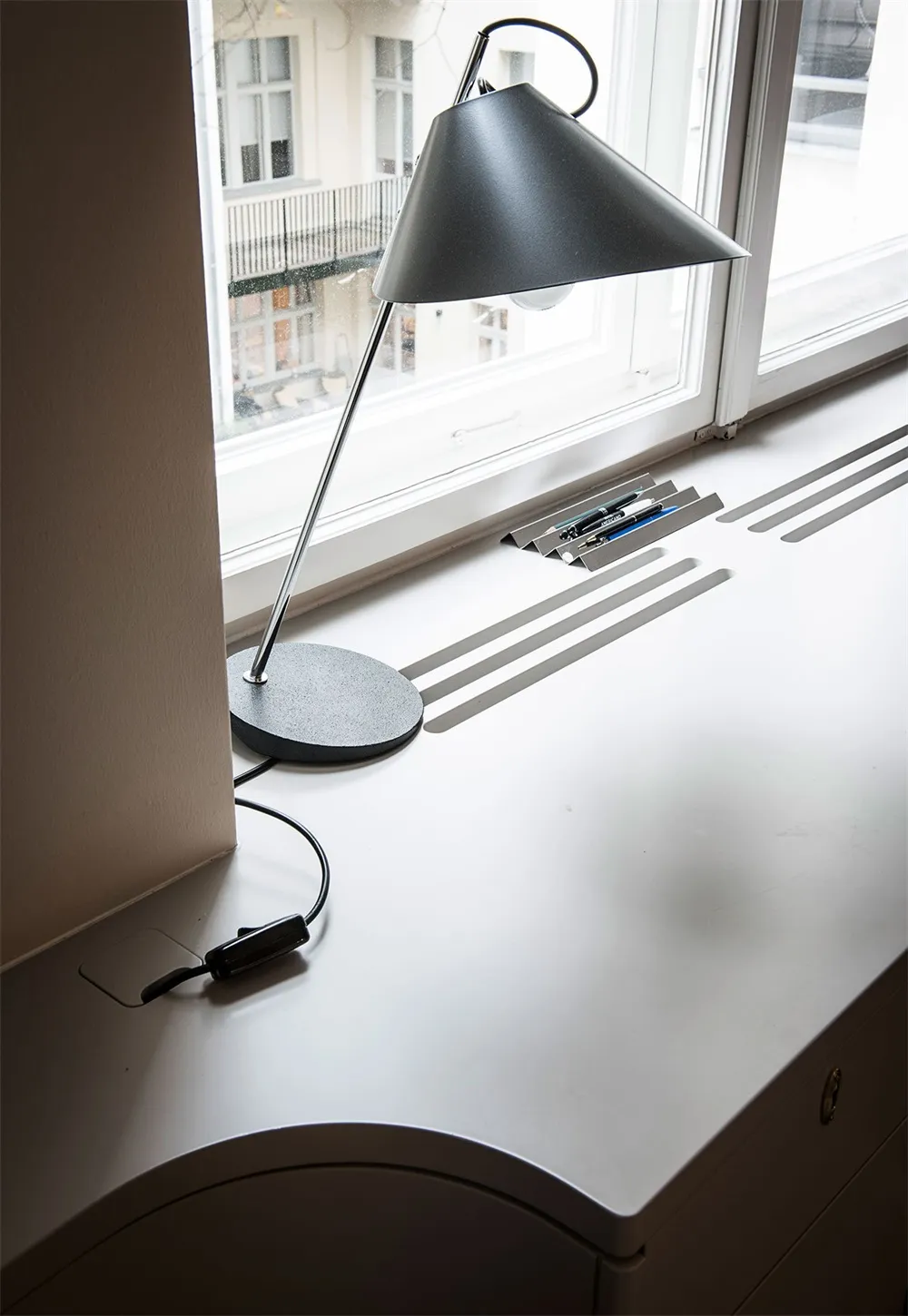A sleek, modern desk space featuring a metallic lamp and desk accessories.