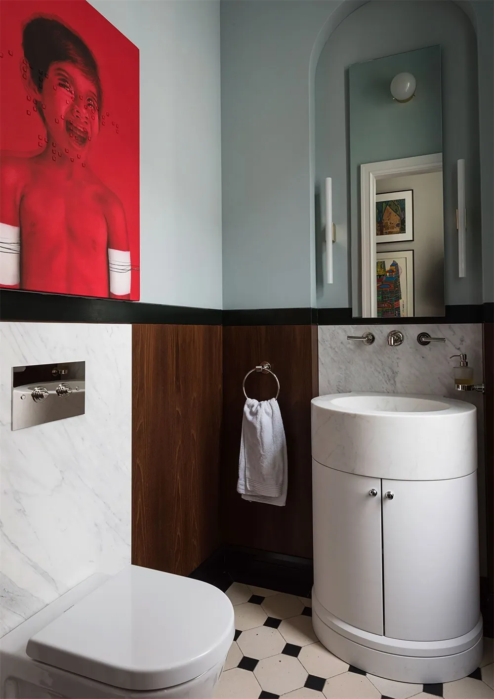 A minimalist bathroom with marble accents and a white toilet, sink, and floor tiles. Features a circular white vanity unit an