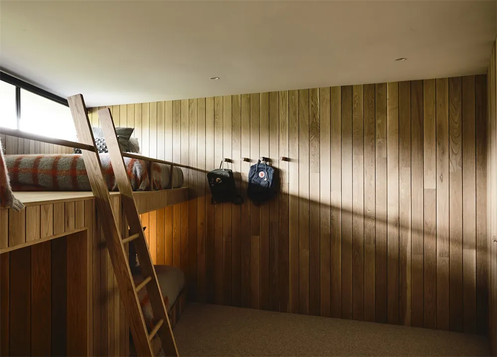 A minimalist bedroom with a wooden bunk bed and a wooden wall paneling.