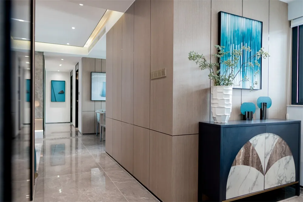 Modern, luxurious entryway with tall wooden walls and a vase of green flowers on a cabinet.