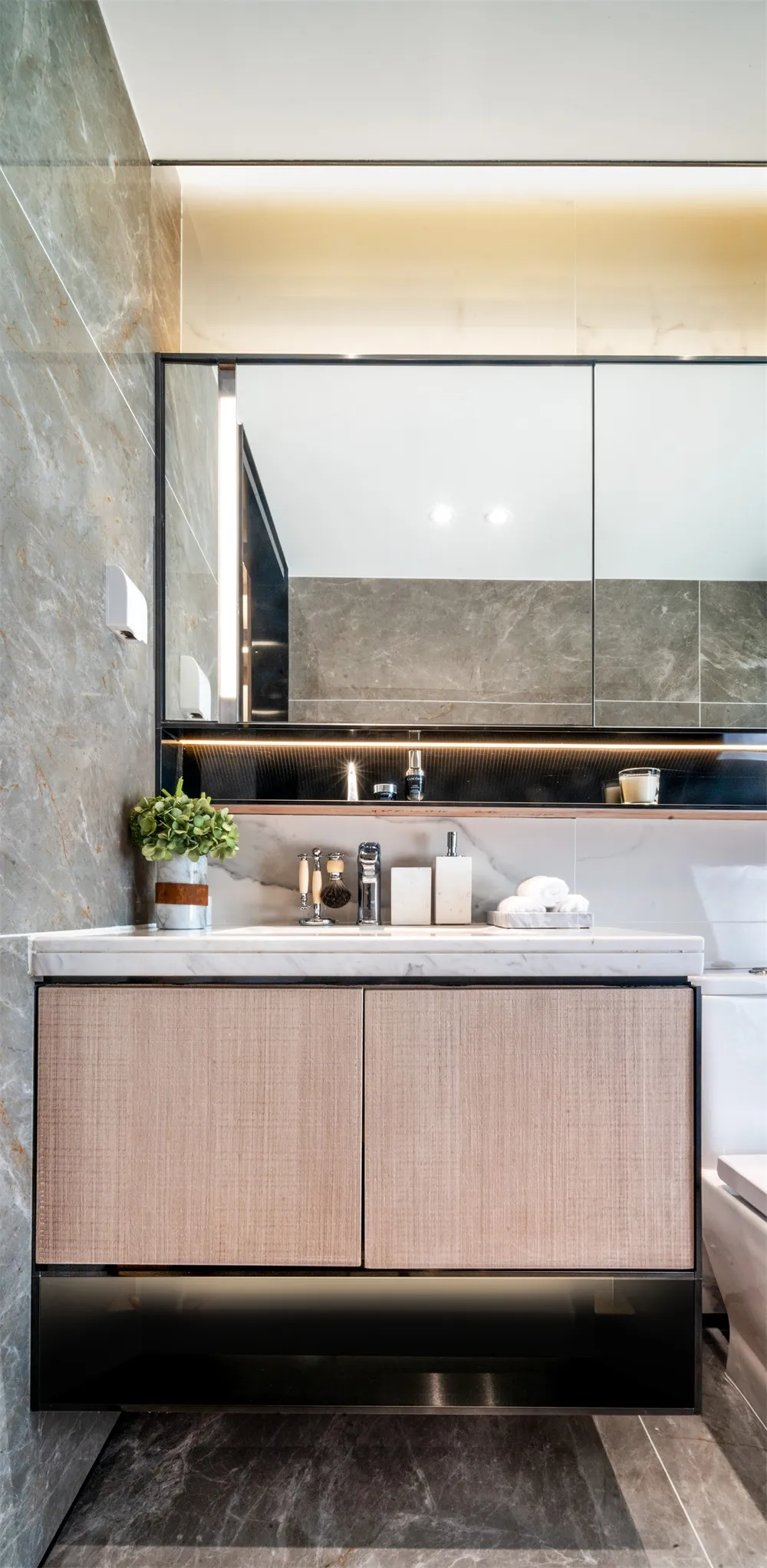 A modern bathroom vanity unit made of marble and wood materials, featuring a mirror cabinet above.