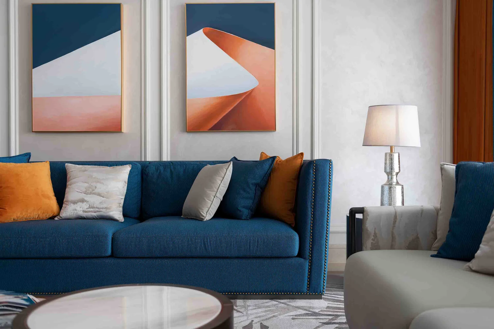 現代客廳內擺放藍色沙發、白色咖啡桌,以及牆上掛著的抽象藝術作品。