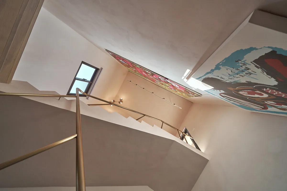 A staircase with a metal handrail and concrete steps set against white walls.