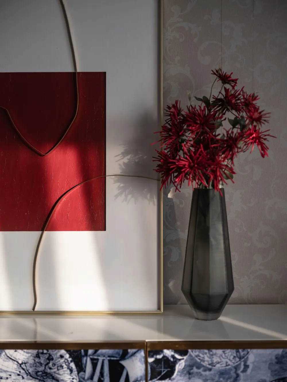 現代室內場景，擺放一隻俐落深色花瓶，插著鮮豔紅色花朵，背景為圖案壁紙與ab