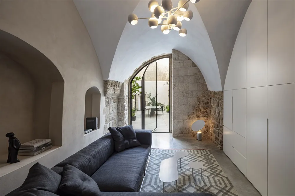 Modern living room with concrete walls, arched ceiling, and minimalist furniture.