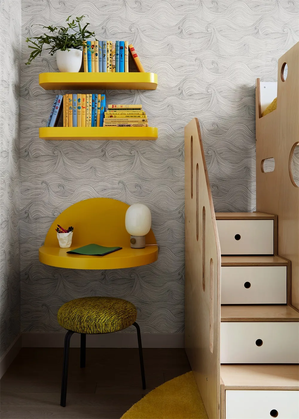 A modern playroom featuring yellow shelves, a desk, and a bunk bed with storage drawers.