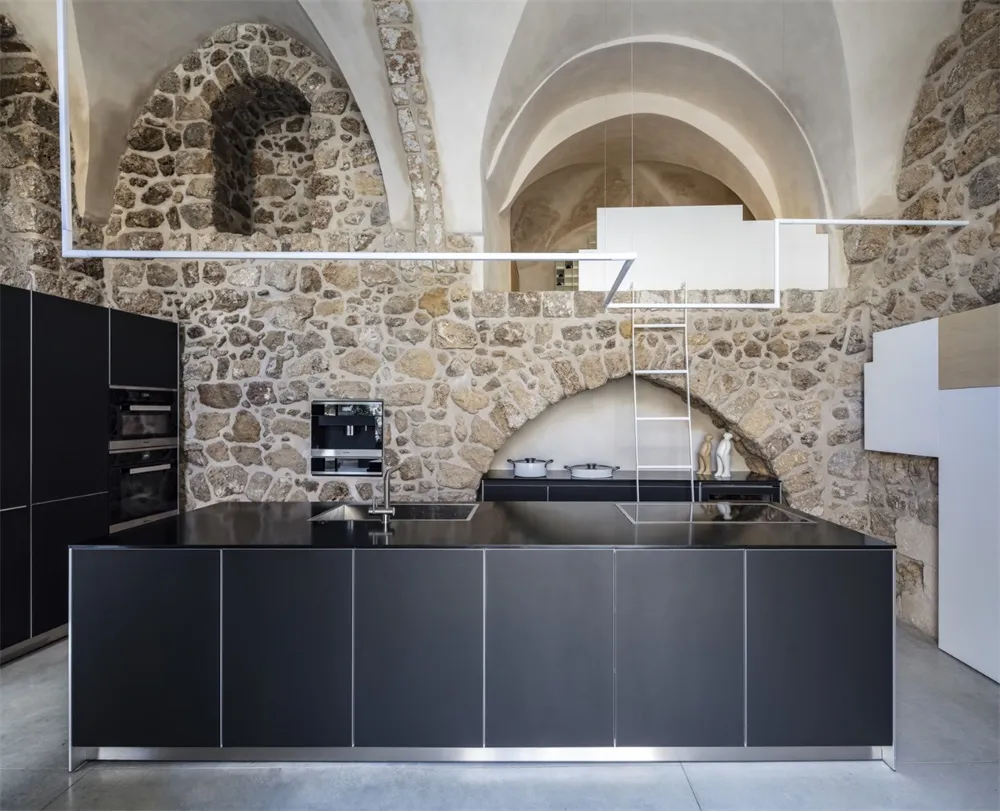 Modern industrial kitchen with stone walls and black metallic surfaces
