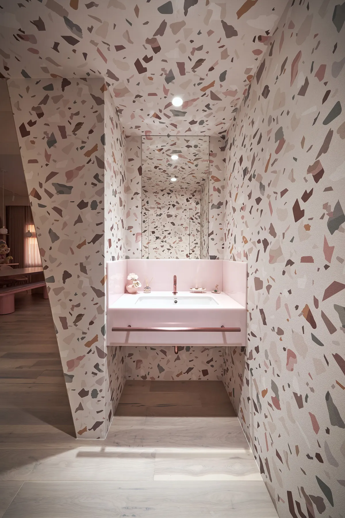 Modern minimalist bathroom with a patterned terrazzo floor and pink sink.