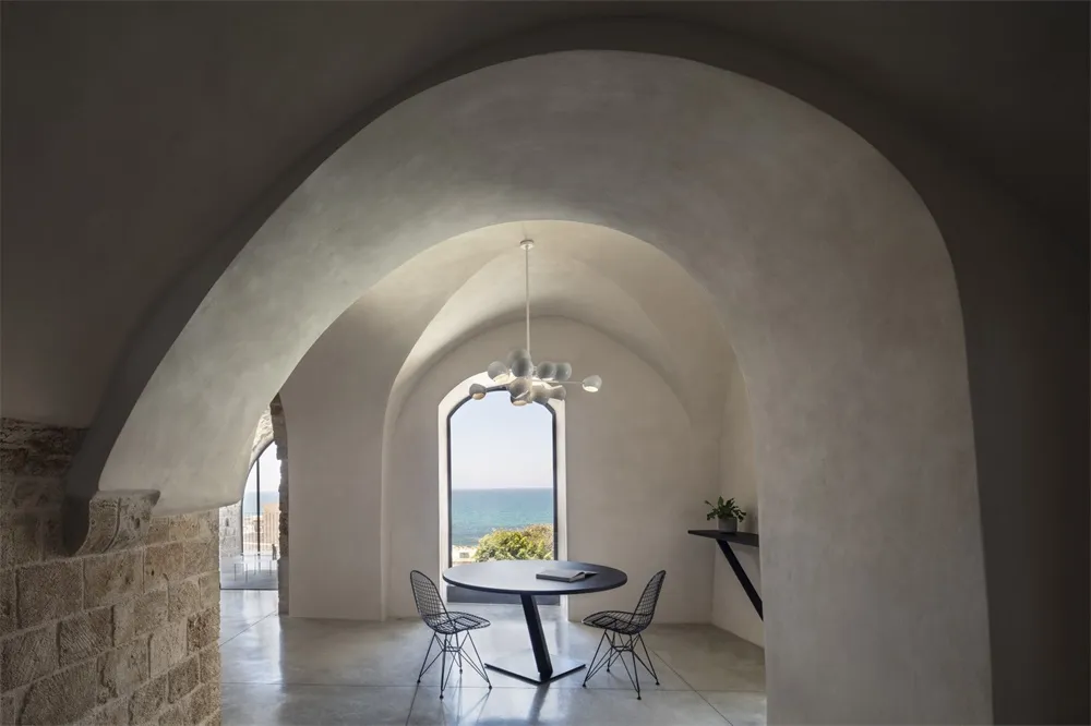 A modern interior with concrete walls and metal accents, featuring a round table and chairs.