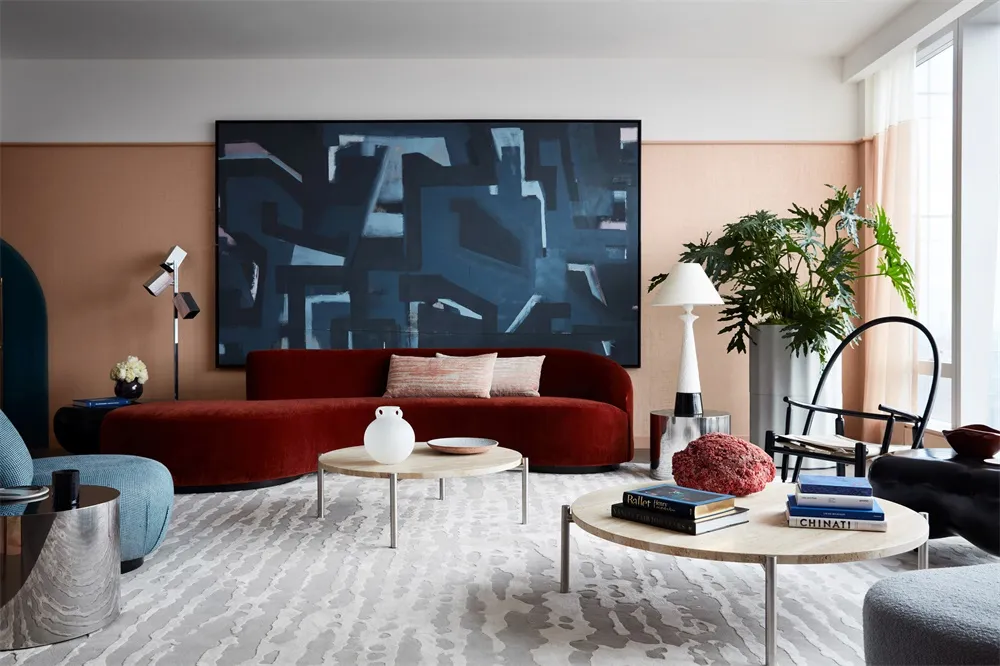 Modern living room featuring a plush velvet couch, wooden tables, and carpet flooring.