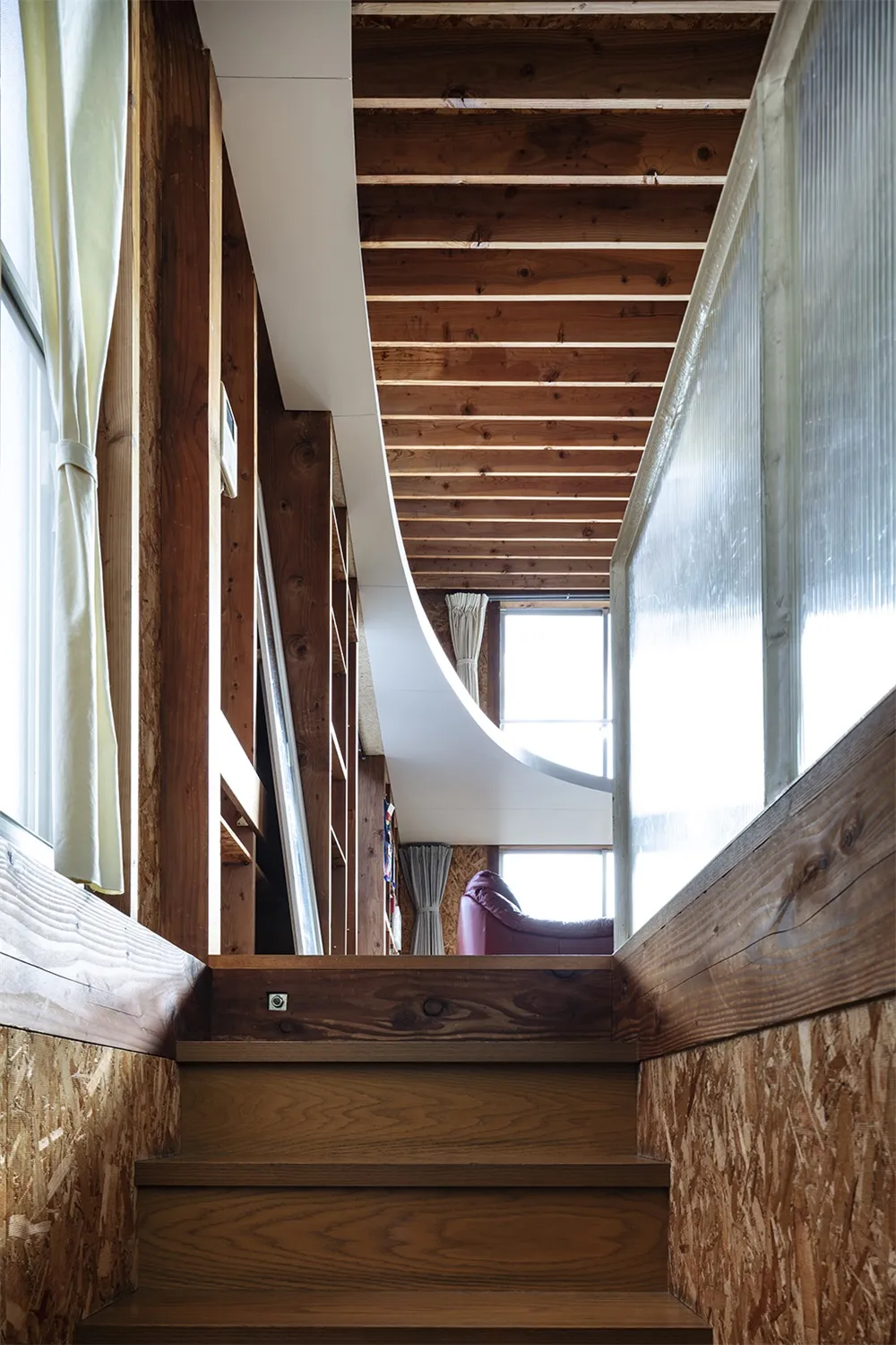 A modern industrial staircase with wooden steps and a white curved railing.