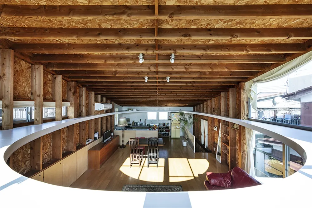 A minimalist apartment with exposed wooden beams and a circular opening in the floor.