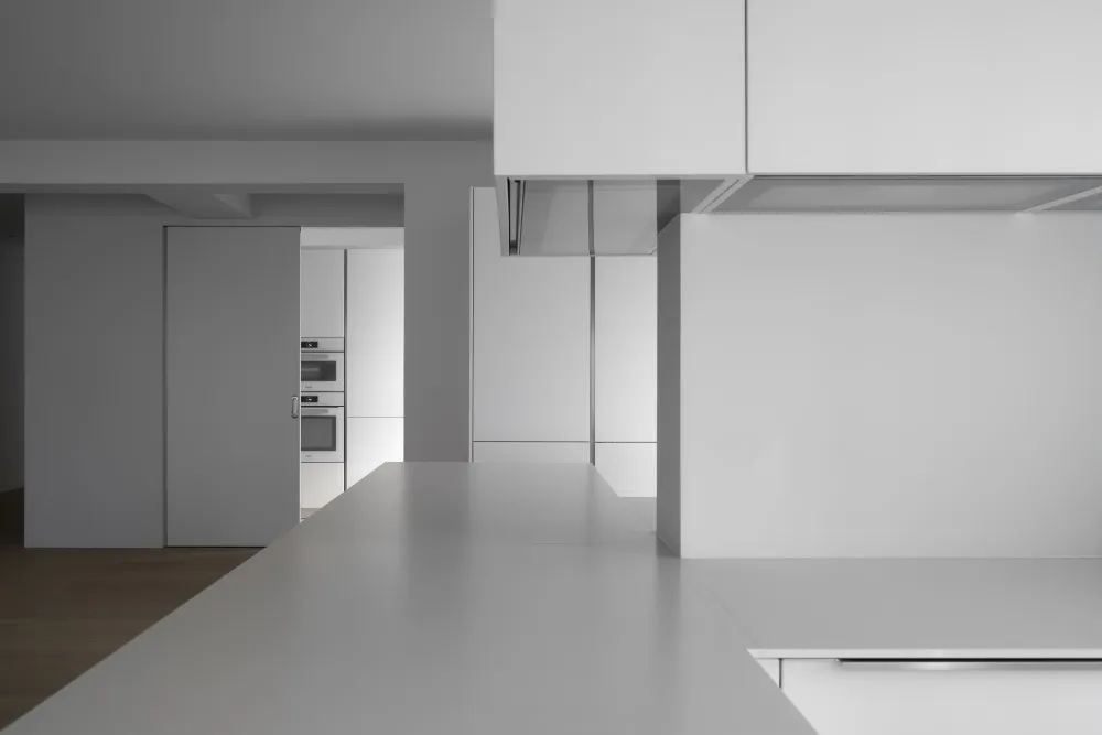 A minimalist kitchen with white cabinets and a clean, uncluttered design.