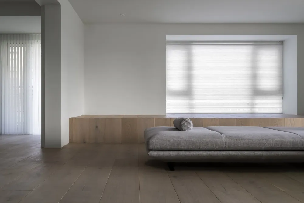 A minimalist living room featuring wood furniture and light-colored fabric.