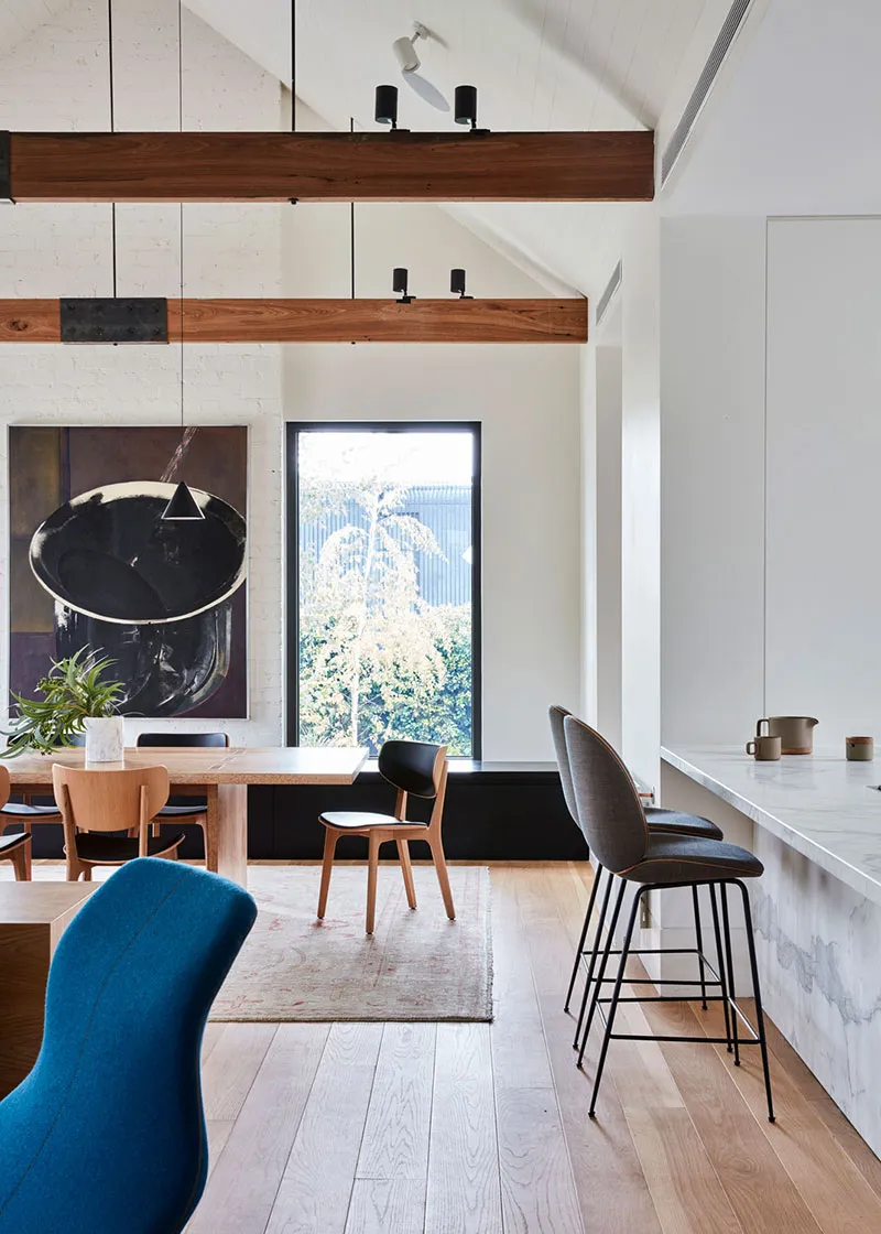 A modern dining room featuring marble countertops, wooden flooring, and upholstered chairs.